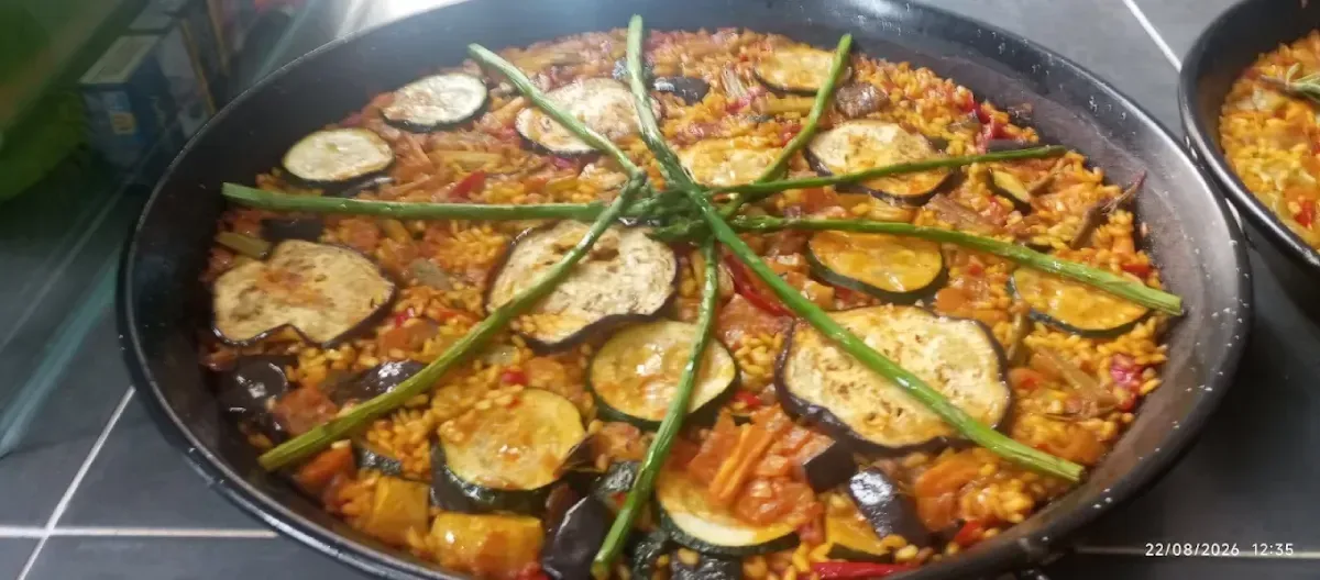 Paella de marisco mixto con judías verdes, servida en una sartén grande negra.