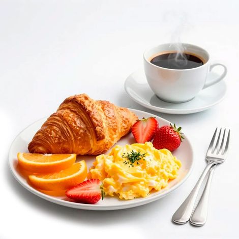 Plato de desayuno con croissant, huevos revueltos, fresas, rodajas de naranja y café.