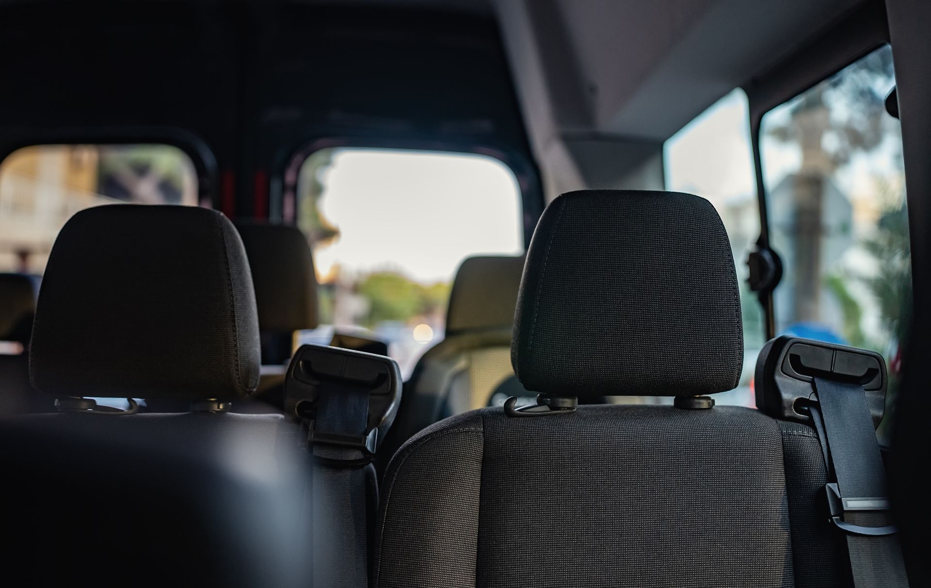 À l'intérieur d'une voiture, deux sièges avant recouverts de housses noires à motifs et une vue floue à travers le pare-brise.