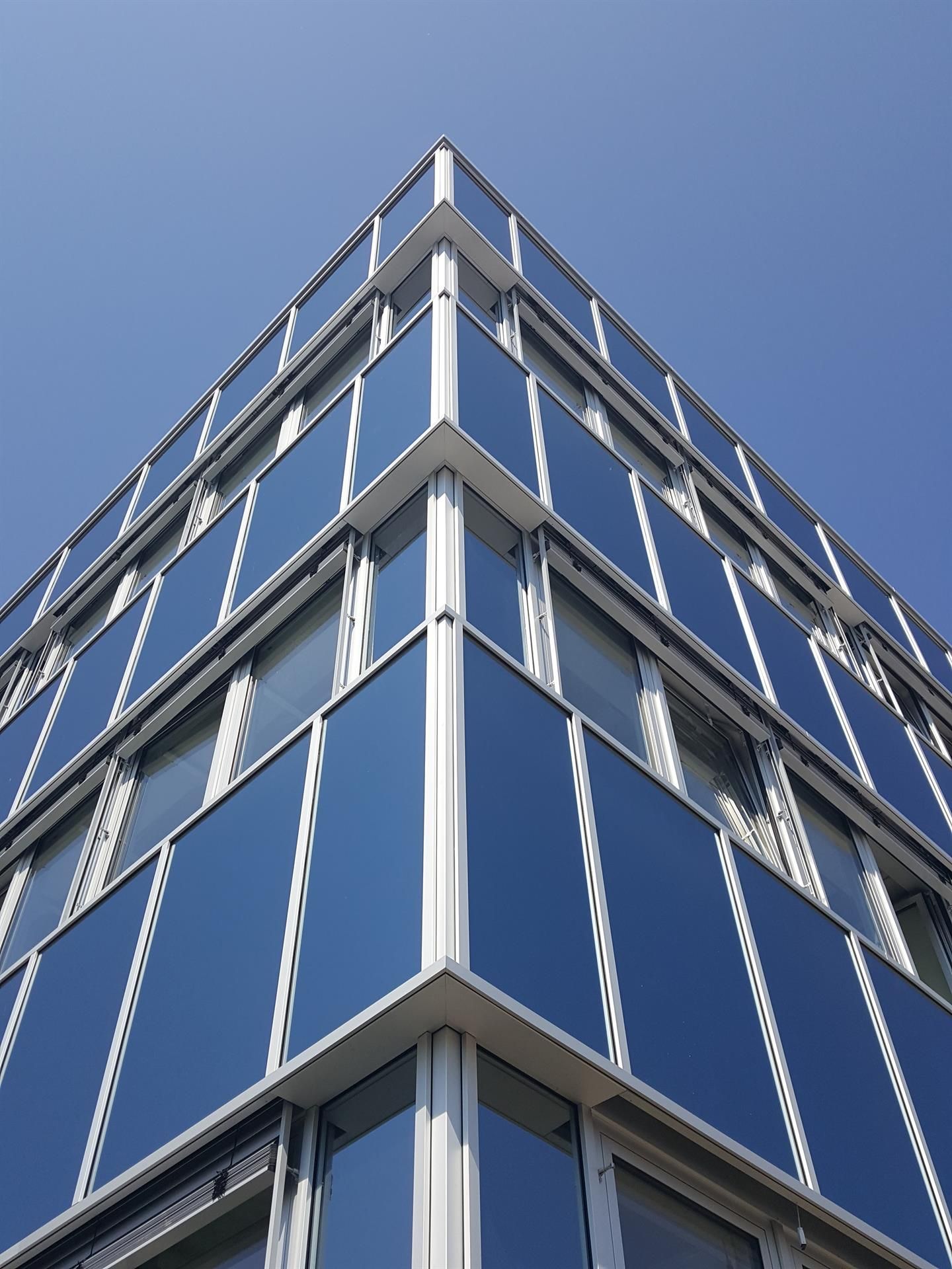 Blick nach oben auf die Ecke eines Gebäudes mit blauen Fenstern