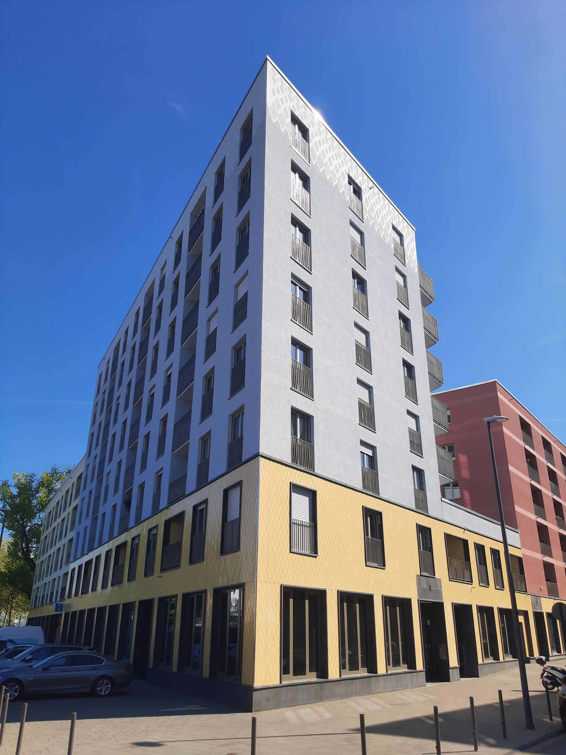 Ein Bauarbeiter mit Schutzhelm und Sicherheitsgurt steht vor einem im Bau befindlichen Gebäude.