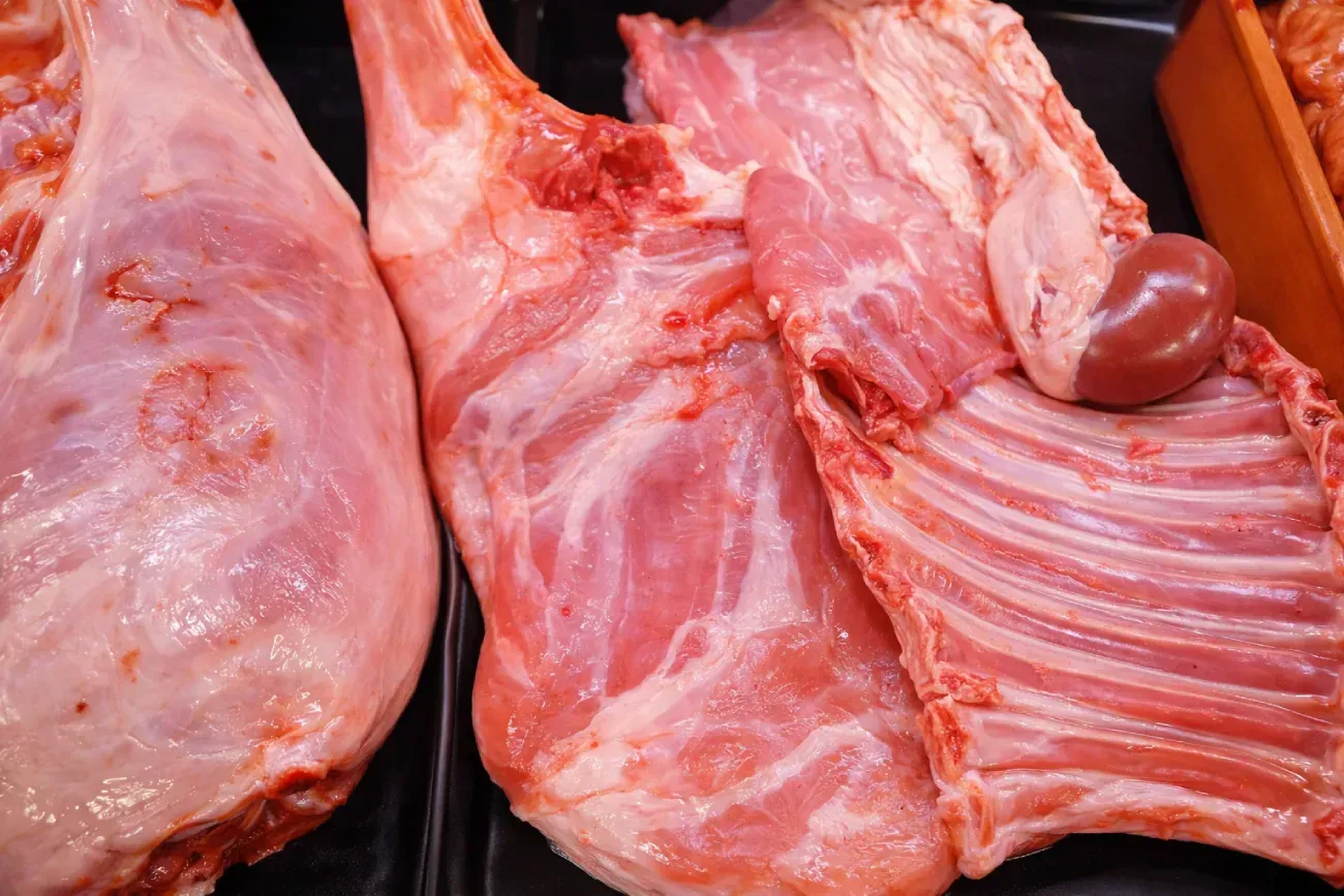 Salchichas en un recipiente blanco, primer plano. Salchichas de color naranja rojizo apiladas.