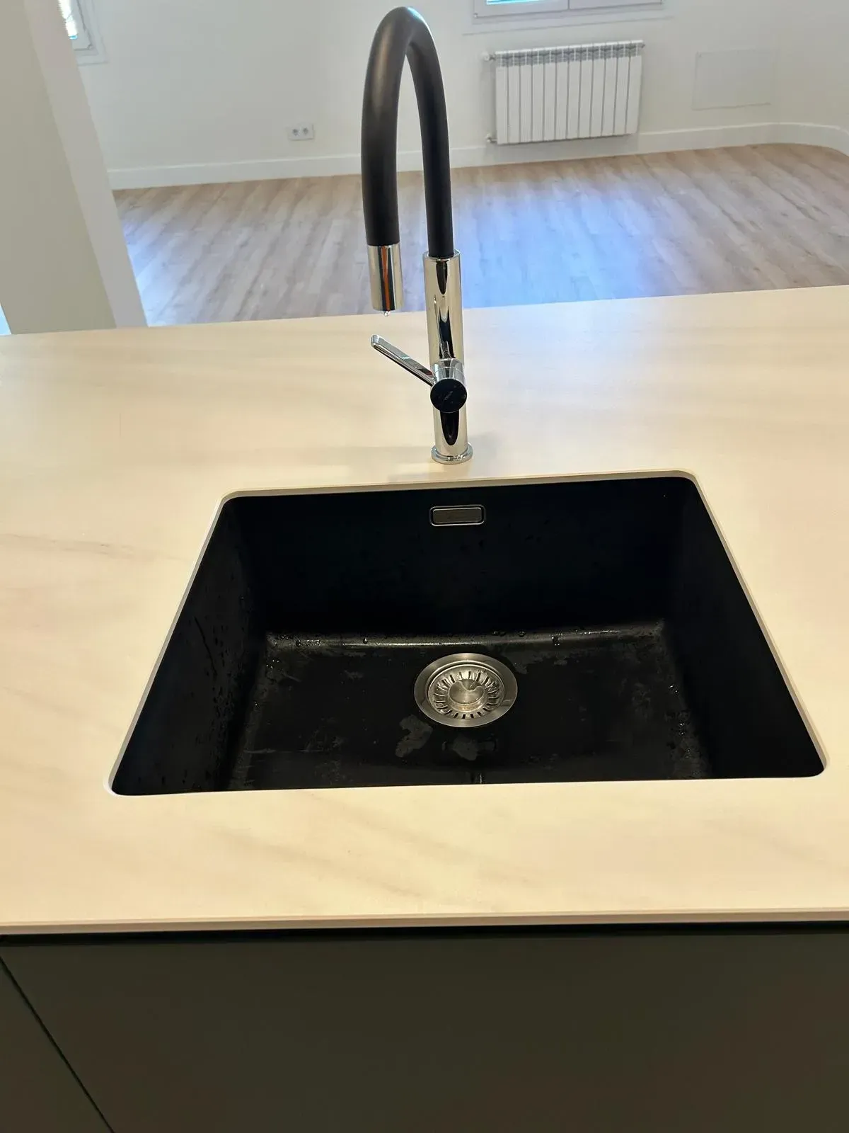 Cocina moderna minimalista con gabinetes de madera, isla con asientos y lámparas colgantes.