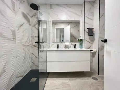 Cocina moderna minimalista con gabinetes de madera, isla con asientos y lámparas colgantes.
