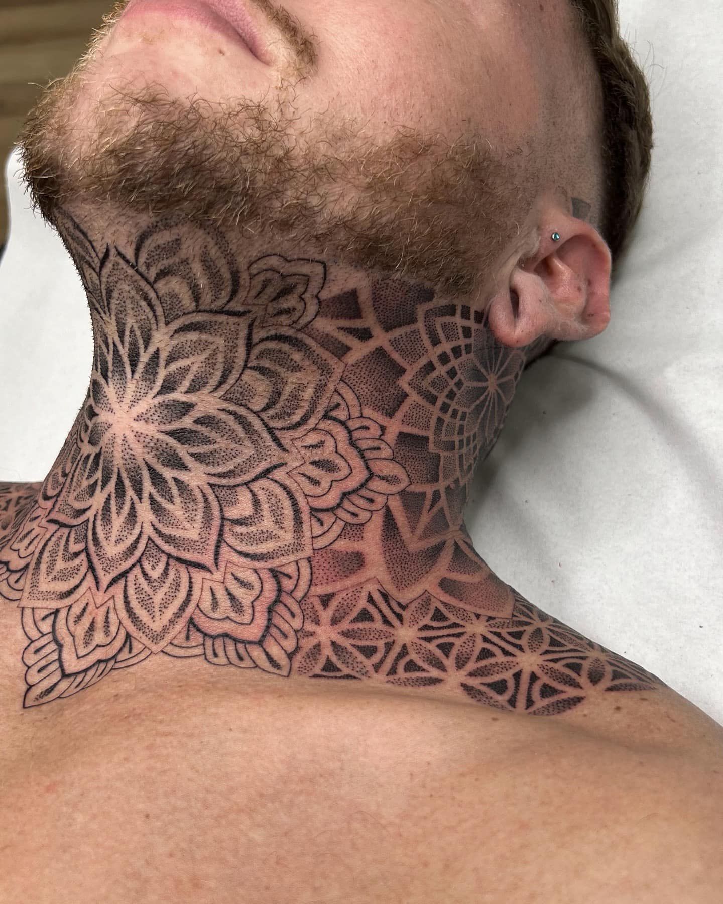 Un hombre con barba tiene un tatuaje en el cuello.