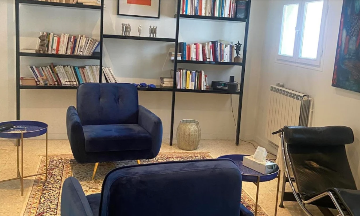 Des fauteuils posés sur un tapis avec en arrière plan des livres posés sur une étagère