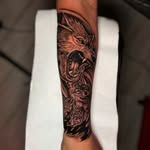 Un tatuaje de tinta negra de un lobo gruñendo en un antebrazo.