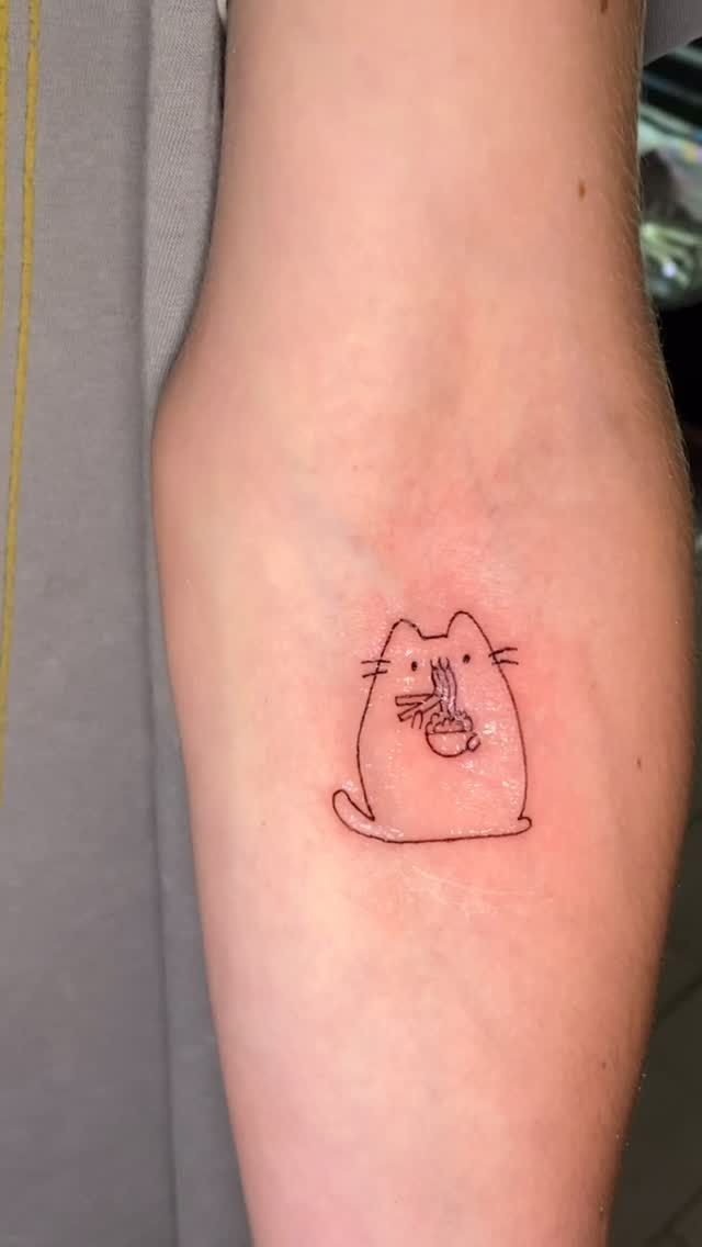 Tatuaje de contorno de un gato de dibujos animados comiendo de un tazón en el brazo de una persona.
