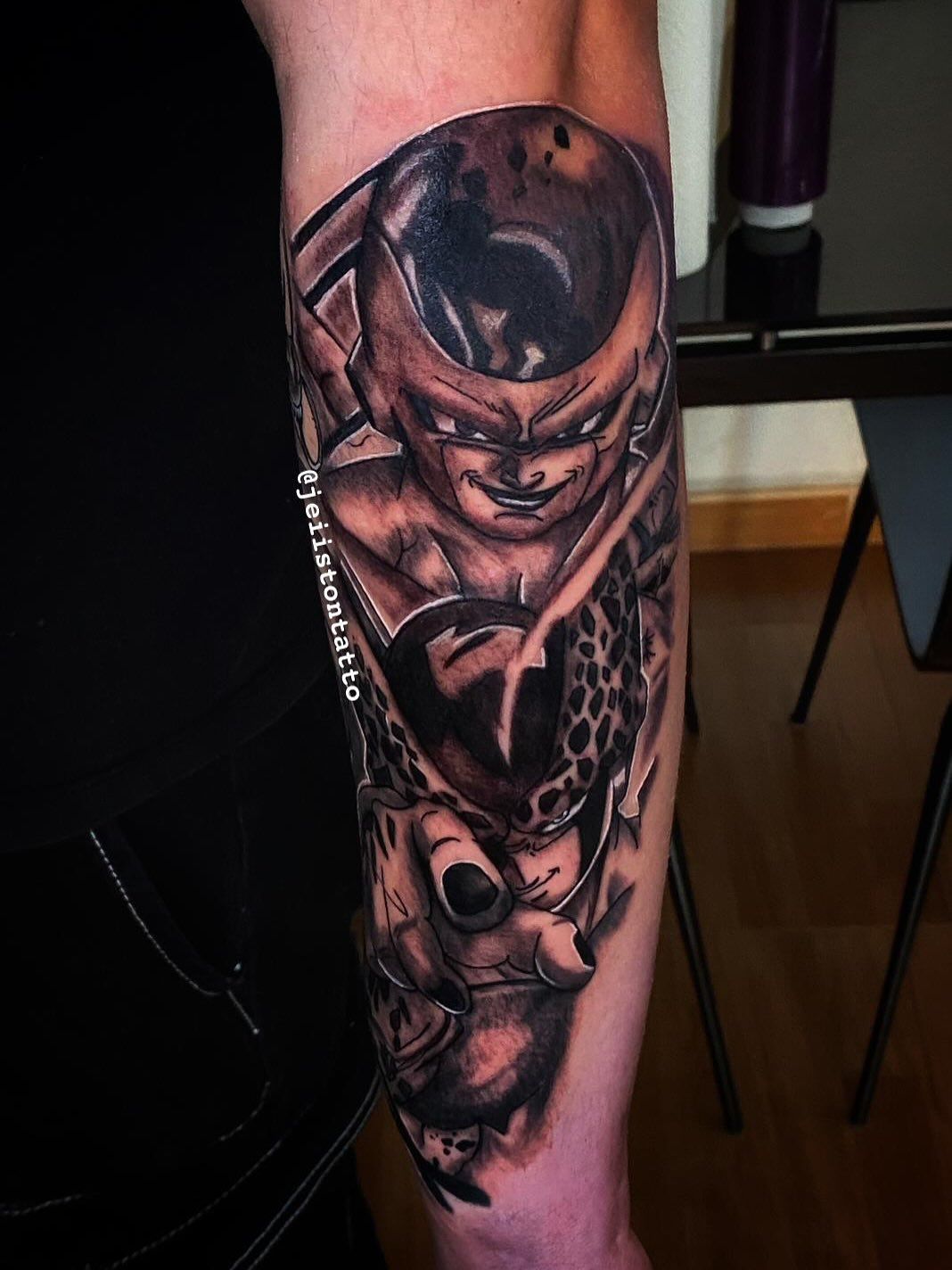 Tatuaje del villano de Dragon Ball Z, Cell, en color negro y gris en un brazo, con fondo negro.