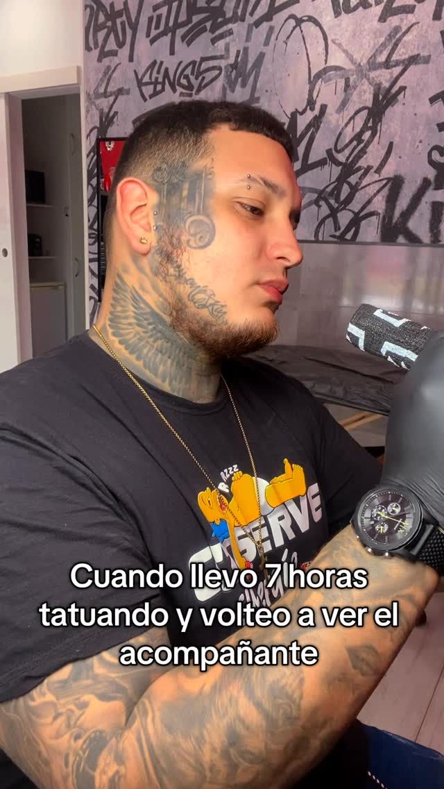 Hombre con tatuajes, mirando su reloj después de 7 horas tatuando. Texto: