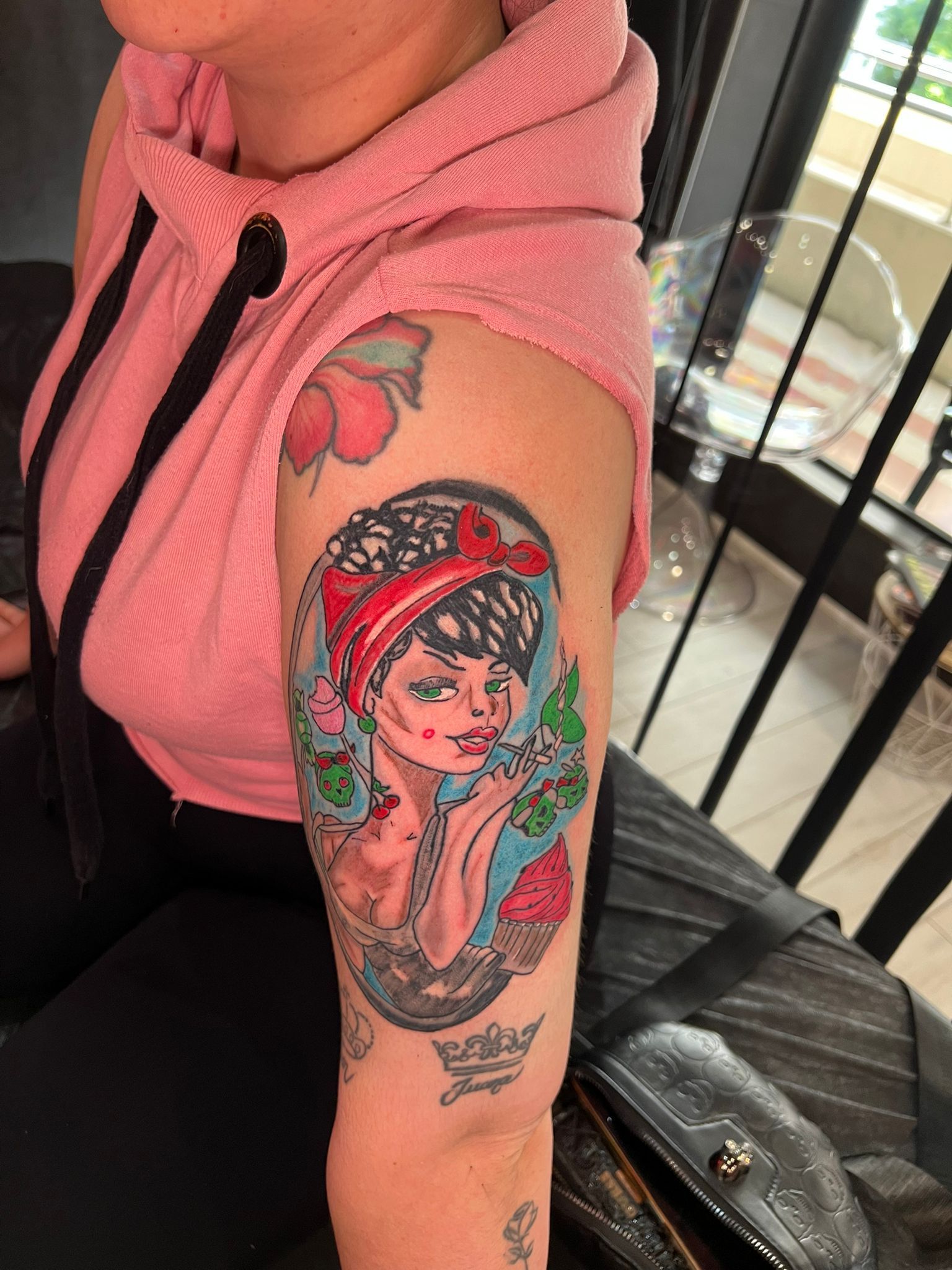 Mujer con un tatuaje de estilo vintage de una mujer que lleva un pañuelo rojo en la cabeza y rosas en la parte superior del brazo.