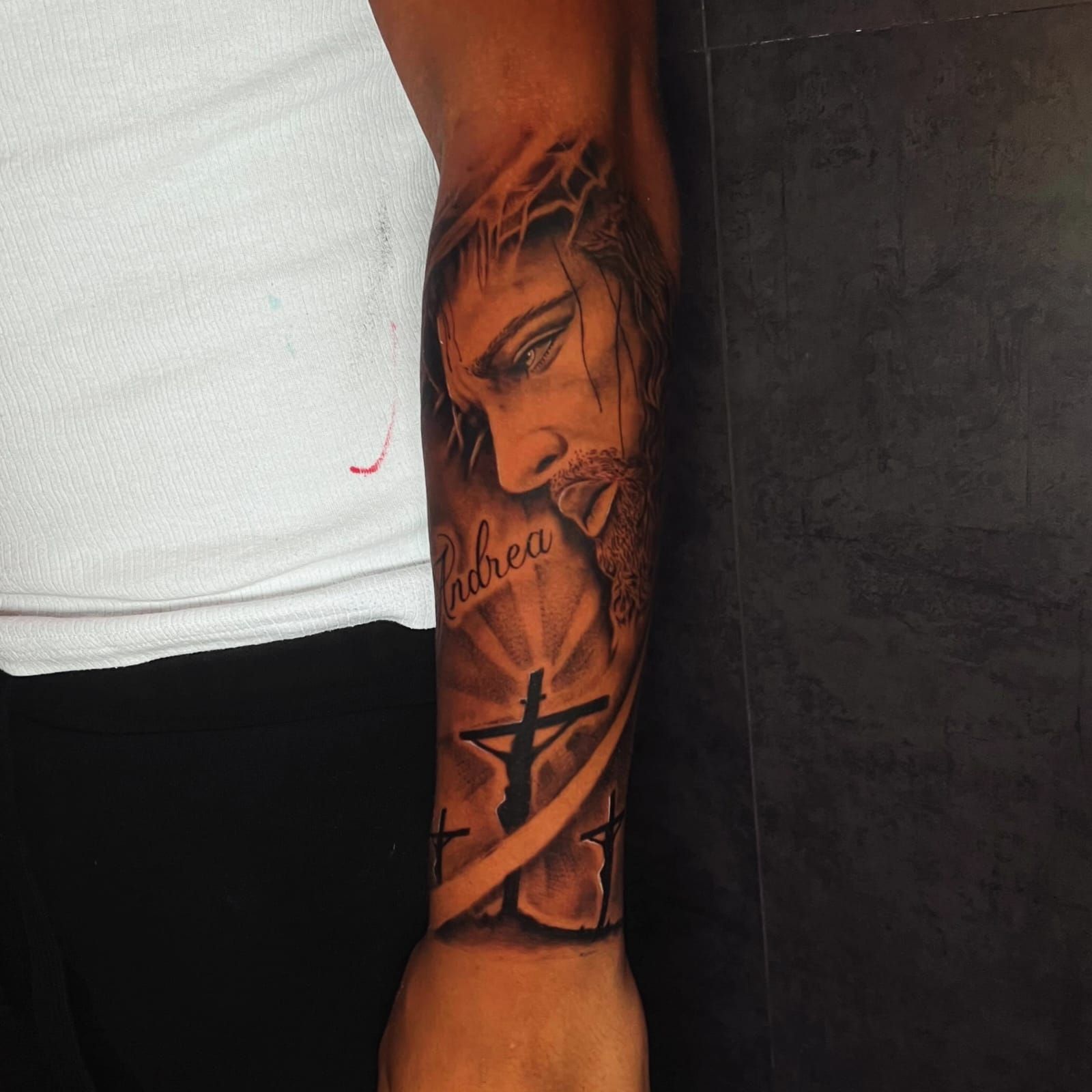 Tatuaje de Jesús con una corona de espinas, dos cruces y el nombre