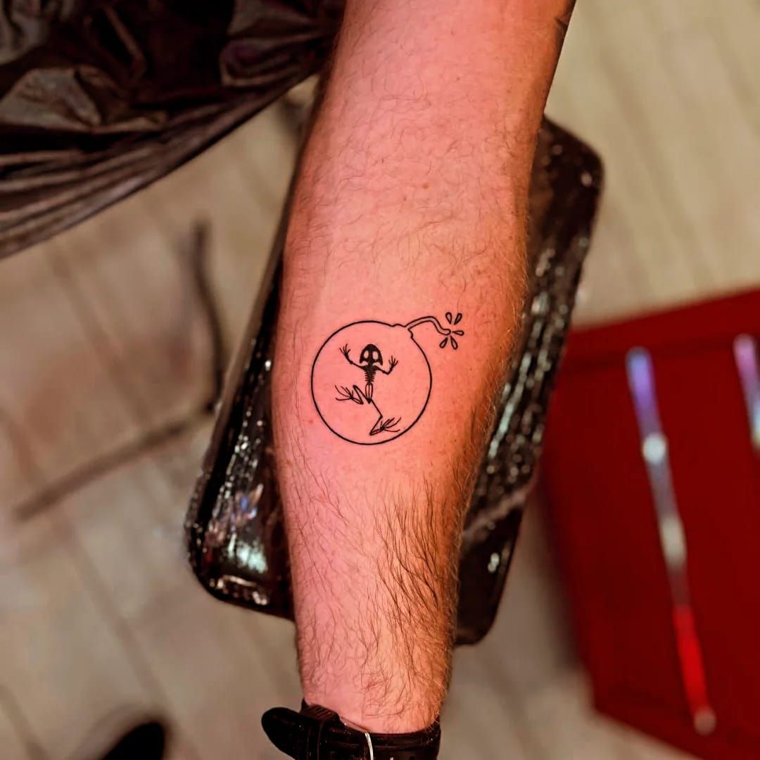 Tatuaje de una rana dentro de una bomba. En una pierna, tinta negra.