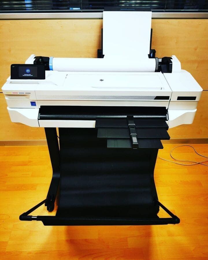 Una impresora HP está sobre un piso de madera.