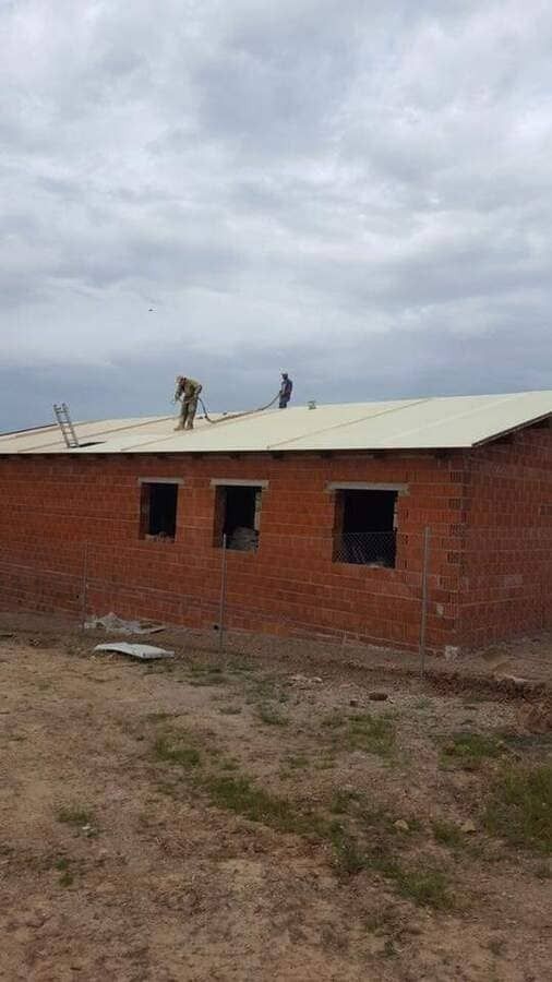 Un grupo de personas está trabajando en el tejado de un edificio de ladrillos.