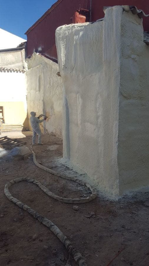 Un hombre está rociando espuma en el costado de un edificio.
