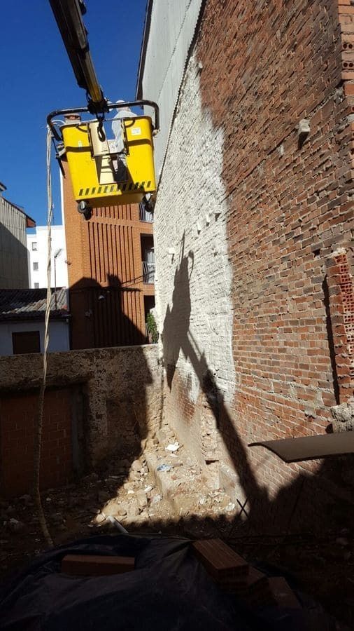 Se está utilizando una grúa amarilla para quitar una pared de ladrillos.