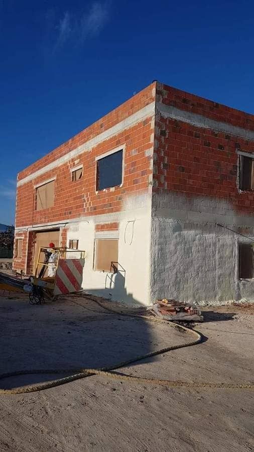 Un edificio de ladrillos está siendo pintado con aerosol blanco.