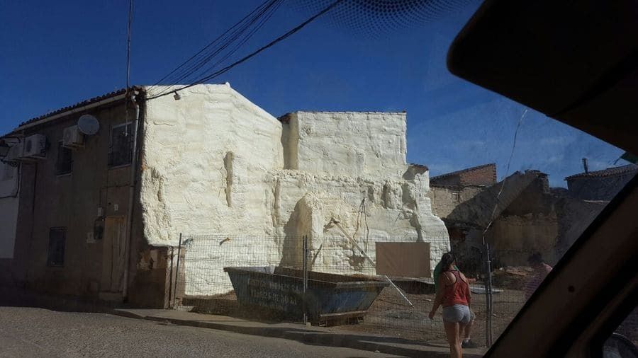 Una mujer camina por una calle frente a un edificio blanco.