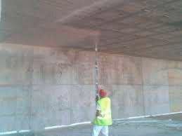 Un hombre está pintando una pared de hormigón con un pincel.