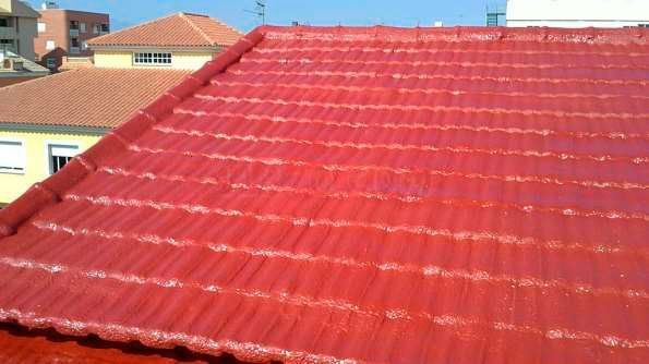 Un techo de tejas rojas con un edificio amarillo al fondo
