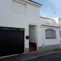 Una casa blanca con una puerta de garaje negra y un portón negro.