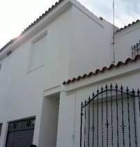 Una casa blanca con una valla negra y un tejado.
