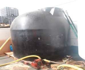 Un gran tanque negro está sobre una mesa al lado de una manguera.