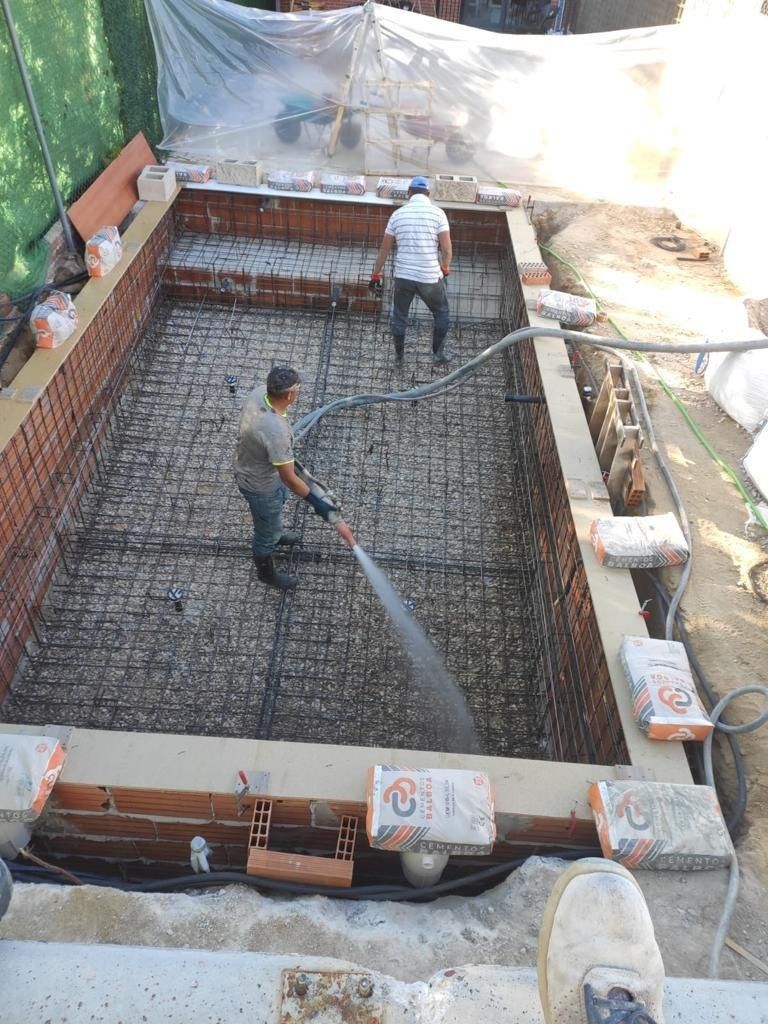 Un hombre está vertiendo hormigón en una piscina.