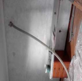 Un baño con un grifo y una manguera colgando de la pared.