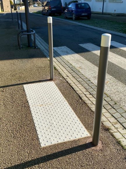 Bornage avec deux piliers en acier et un marquage au sol pour indiquer un passage piéton en trottoir
