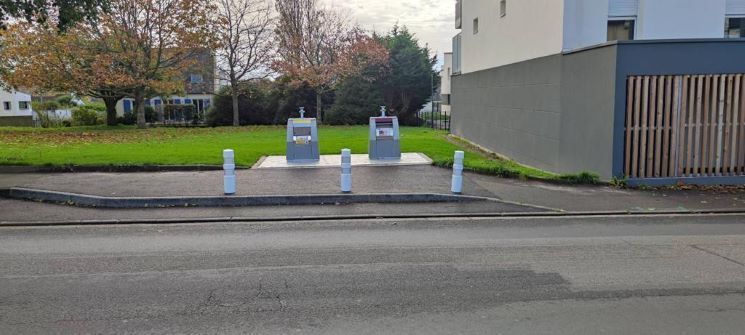 Bornage d'un trottoir avec un mobilier urbain devant une zone de tri des déchets