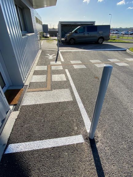 Marquage au sol devant une entreprise privée pour un passage piéton et la zone de l'entrée