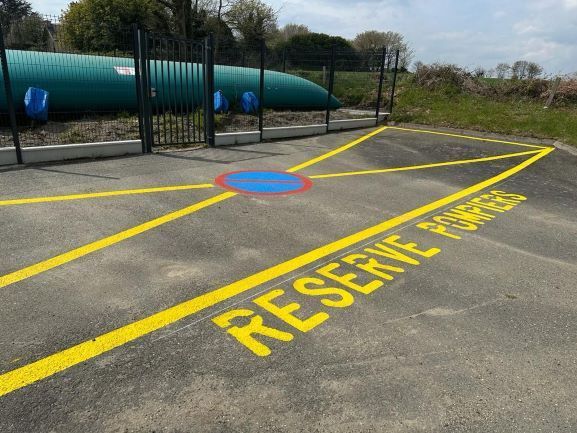 Zone de parking réservée aux pompiers devant une citerne à eau marquée au sol en jaune