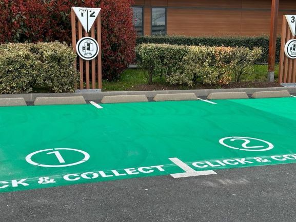 Marquage au sol en vert clair devant une zone de click & collect pour les voitures de passage
