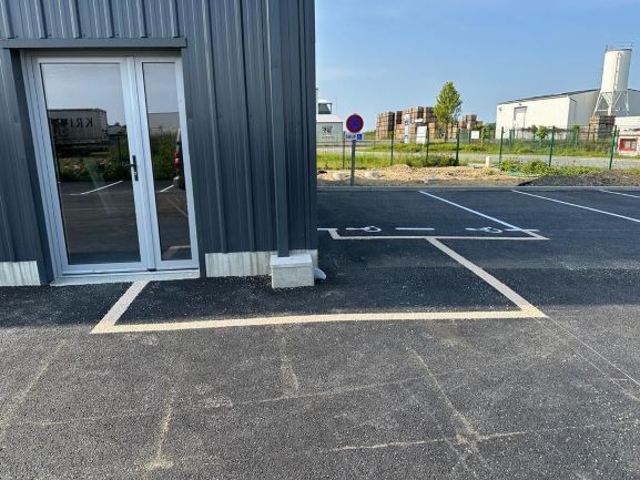 Marquage au sol devant un édifice pour la place de parking PMR ainsi que la zone piétonne d'accès