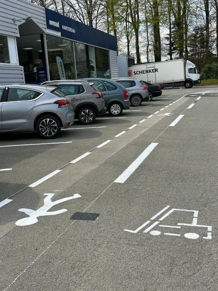 Marquage blanc sur le sol d'un parking ouvert pour les places et la zone piétonne