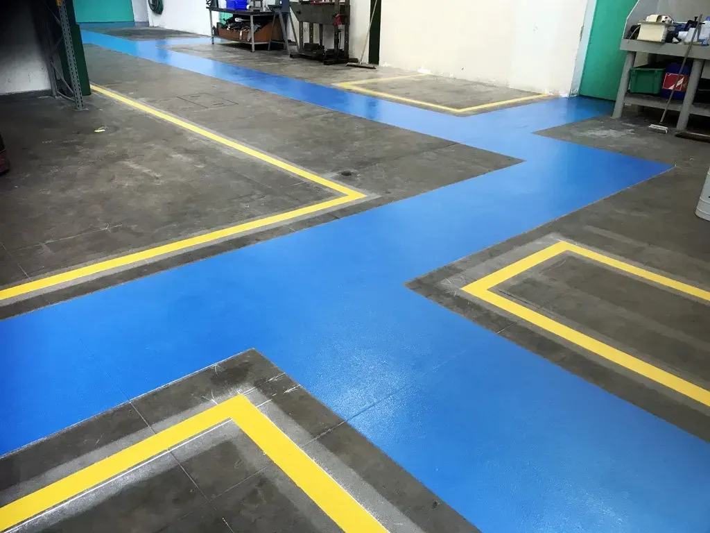 Marquage au sol en entrepôt industriel pour indiquer les zones de circulation et de travail