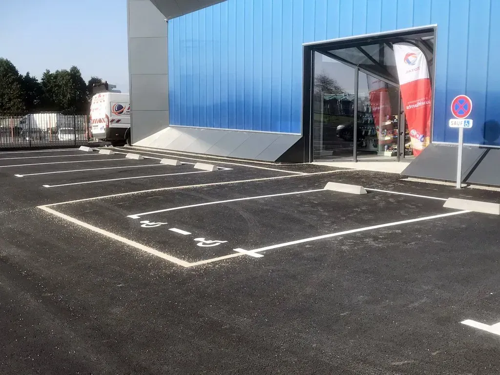 Marquage au sol devant une structure professionnelle pour les zones de parking et notamment l'espace de parking PMR