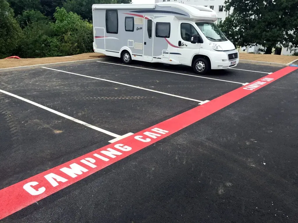 Marquage au sol de la zone de parking extérieur pour les camping car avec une couleur rouge et l'ecriture blanche