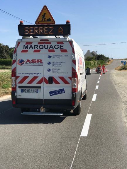 Camion d'ASR vu de dos sur une route de campagne lors d'une intervention de marquage au sol