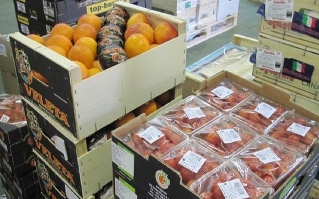 Des caisses en bois remplies d'oranges et de tomates emballées dans un entrepôt de produits frais.