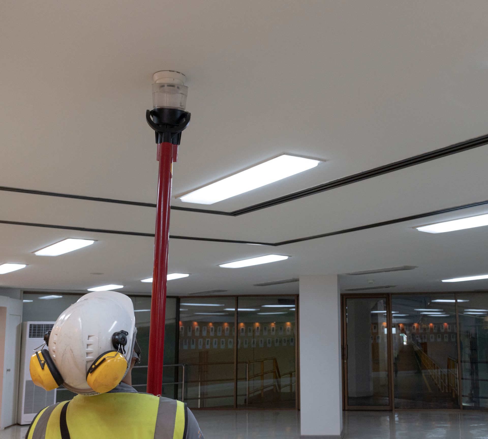 Une personne en tenue de sécurité regarde un gyrophare rouge fixé au plafond.