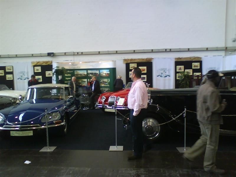 Ein Mann in einem rosa Hemd steht vor einem blauen Auto