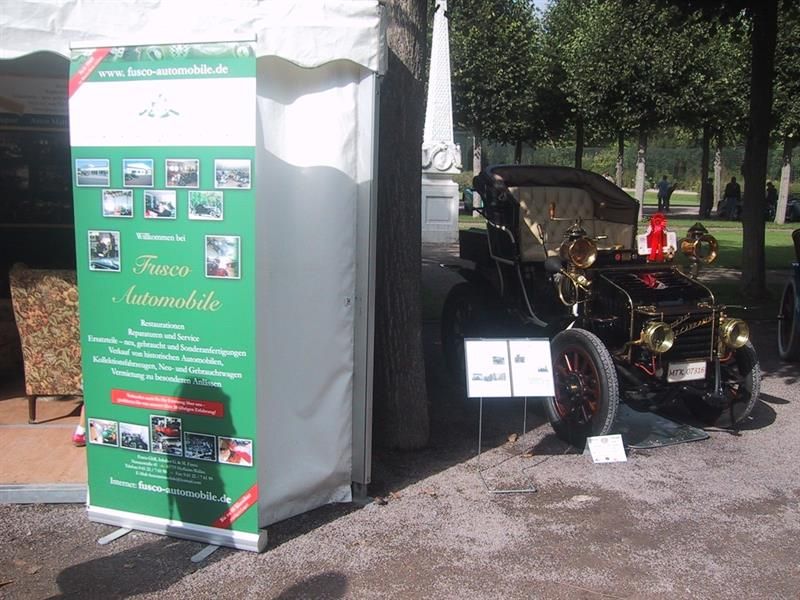 Ein altes Auto steht neben einem Schild mit der Aufschrift „Frauen Automobile“