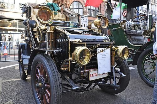 Auf der Straße parkt ein altes Auto mit dem Nummernschild „HTN“.