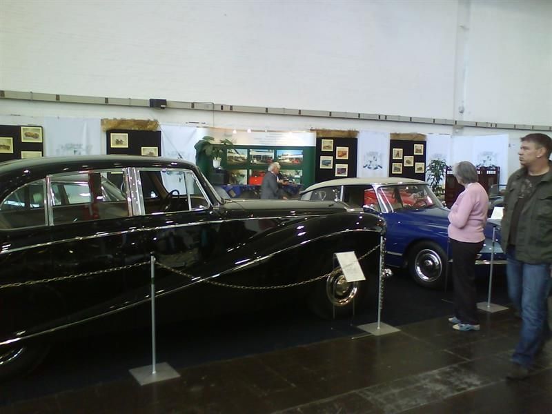 Eine Gruppe von Menschen steht um eine Ausstellung von Autos herum