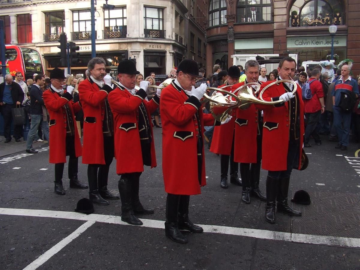 Eine Gruppe von Männern in roten Mänteln spielt Hörner