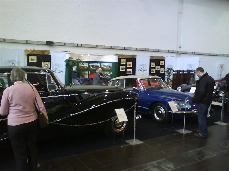 Eine Gruppe von Menschen schaut sich in einem Museum alte Autos an