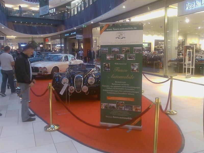 Ein Mann steht vor einem Schild mit der Aufschrift „Fiere Automobile“